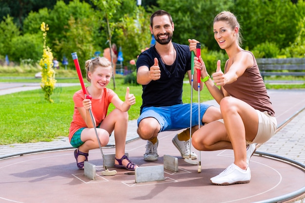 Familie die miniatuurgolf op de zomerdag speelt