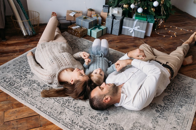 Familie die op de vloer thuis ligt. Geschenkdozen en kerstboom