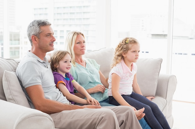 Familie die op TV let terwijl het zitten op bank