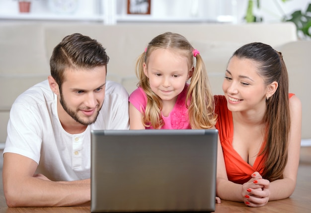 Familie die op vloer ligt die thuis laptop thuis met behulp van.