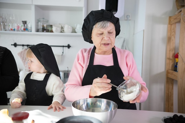 Familie die pannenkoeken maakt een oude vrouw die het deeg op de pan legt