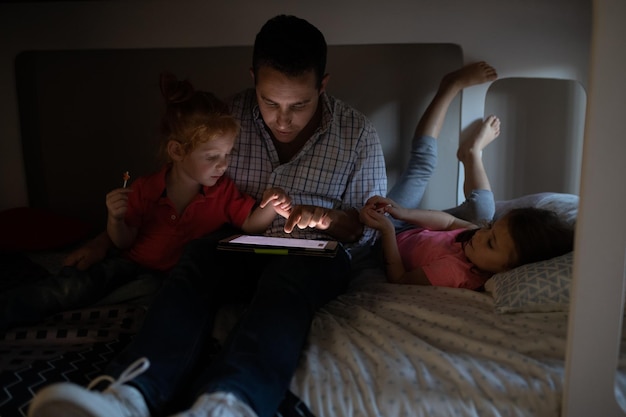 Familie die thuis een digitale tablet gebruikt op het bed in de slaapkamer