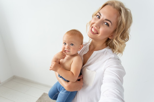 Familie en moederschap concept - gelukkige jonge blonde moeder met kleine baby selfie te nemen.