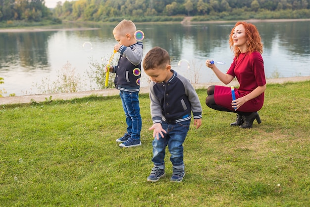 Familie en natuur concept - moeder en hun kinderen spelen met kleurrijke zeepbellen.