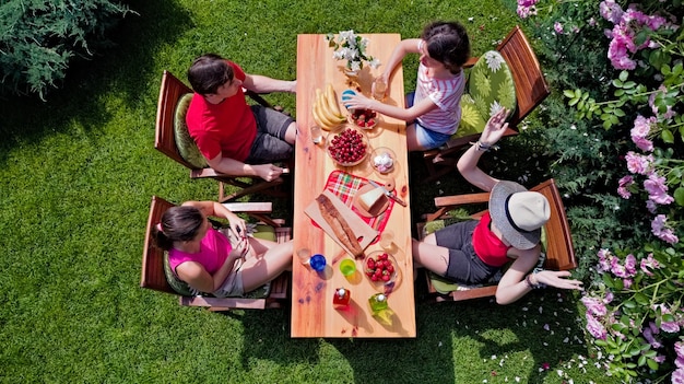 Familie en vrienden die samen buiten eten op zomertuinfeest luchtfoto van tafel met eten