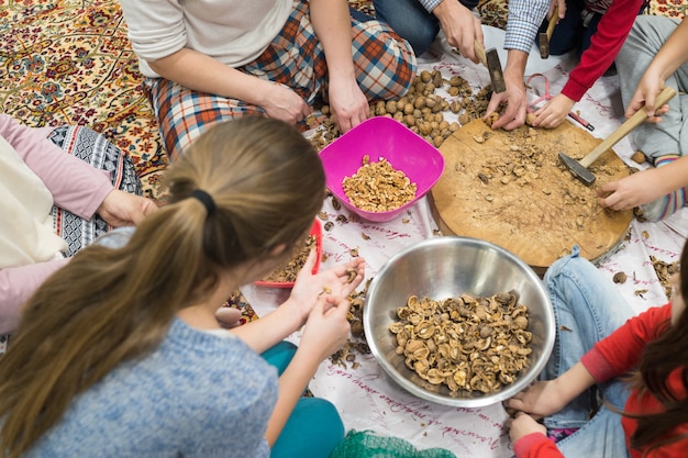 Familie en vrienden kleine bedrijfszitting op grond en brekende okkernoten