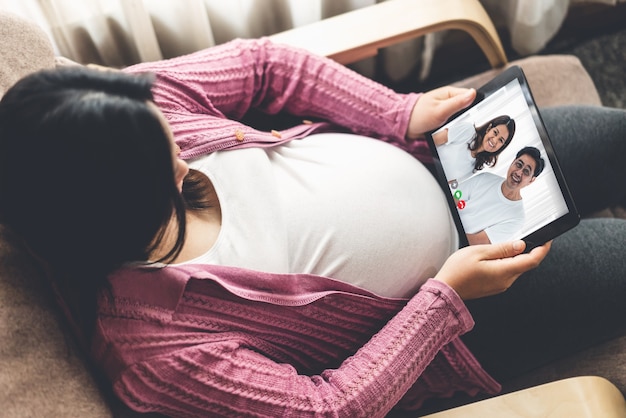 Familie en zwangere vrouw videogesprek terwijl ze veilig thuis blijven tijdens covid-19