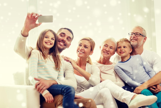 familie, geluk, generatie en mensen concept - gelukkige familie zittend op de bank en selfie nemen met smartphone thuis