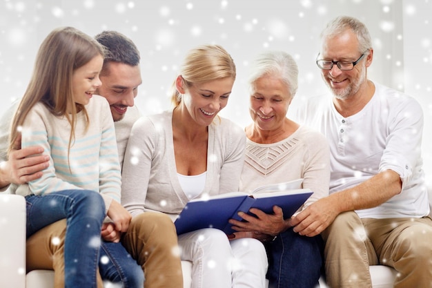 Foto familie, geluk, generatie en mensenconcept - gelukkig gezin met boek of fotoalbum dat thuis op de bank zit