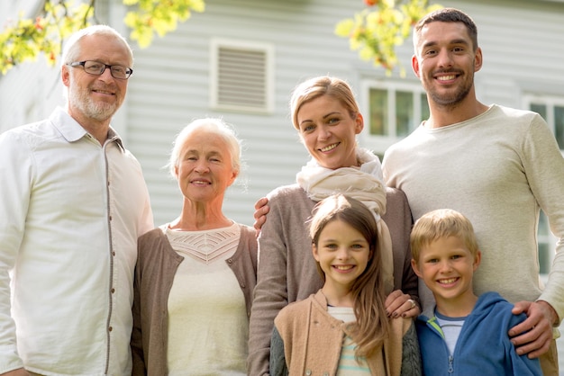 familie, geluk, generatie, huis en mensenconcept - gelukkige familie die buiten voor huis staat