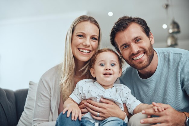 Familie gelukkig portret en ontspannen met baby op de bank in de woonkamer voor liefdesondersteuning en quality time hechting Ouders glimlachen terwijl ze kind en geluk bij elkaar houden voor vertrouwen op de bank in het ouderlijk huis