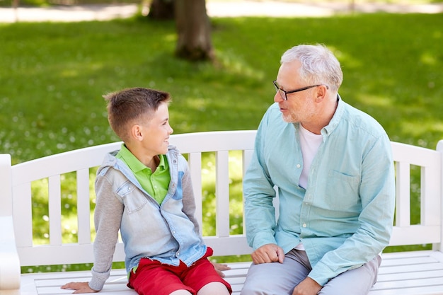 familie-, generatie-, communicatie- en mensenconcept - gelukkige grootvader en kleinzoon praten in het zomerpark