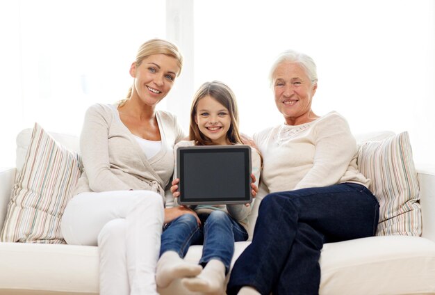 familie, generatie, technologie en mensen concept - lachende moeder, dochter en grootmoeder met tablet pc-computer zittend op de bank thuis