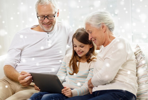 familie, generatie, technologie en mensenconcept - glimlachende grootvader, kleindochter en grootmoeder met tablet-pc-computer die thuis op de bank zit