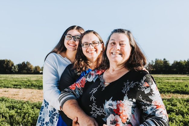 Familie grootmoeder moeder en dochter glimlachend in het midden van het veld op een zonnige dag middag