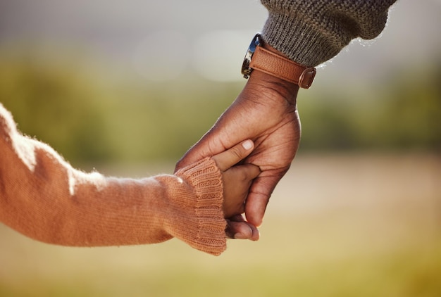 Foto familie hand in hand en meisje met vader close-up in een park handen en wandelen in de natuur band en ontspannen buitenshuis liefde vertrouwen en ouder handen met kind ter ondersteuning van vertrouwen, vrede en eenheid