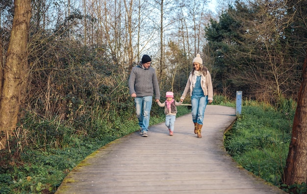 Familie hand in hand terwijl ze over een houten pad het bos in lopen