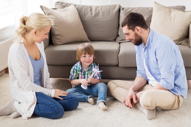 familie, hernieuwbare energie, ecologie en mensenconcept - gelukkige kleine jongen en ouders die thuis met speelgoedwindturbine spelen