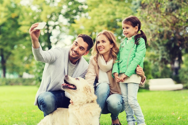familie, huisdier, dier, technologie en mensen concept - gelukkig gezin met labrador retriever hond die selfie maakt met smartphone in het park