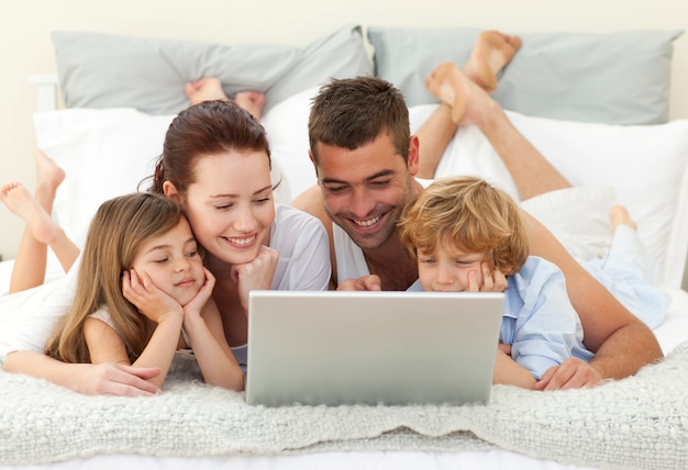 Foto familie in bed met behulp van een laptop