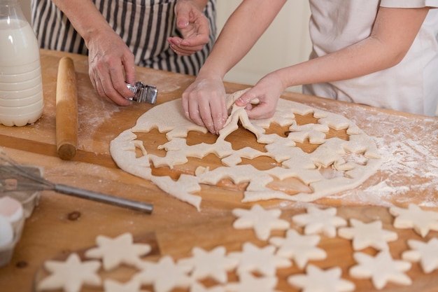 Familie in de keuken Grootmoeder kleindochter kind handen koekjes van deeg op keukentafel samen snijden Oma leert kind meisje koken koekjes bakken Huishoudelijke teamwerk familie generaties helpen