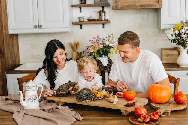 Familie in de keuken. mooie moeder met haar zoontje. veel oogst pompoen, zonnebloem, appels.