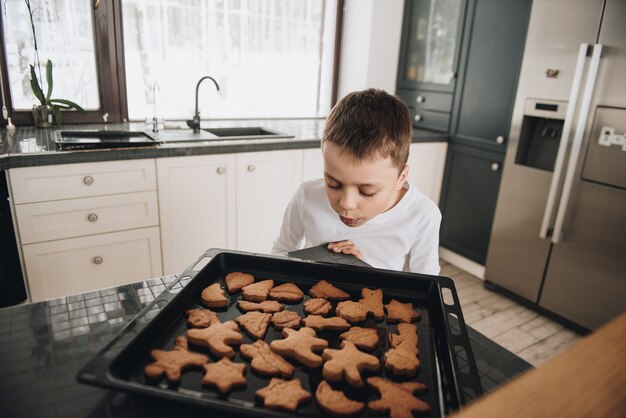 Familie in een groot huis. Lifestyle Thuiscomfort. Kinderen thuis. Bak peperkoekkoekjes met mama. Klaar hete koekjes. Mooie keuken.