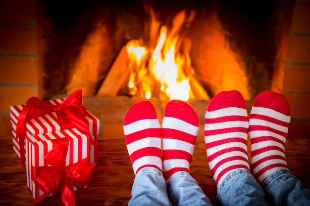 Familie in kerstsokken in de buurt van open haard. Moeder; vader en baby hebben samen plezier. Mensen die thuis ontspannen