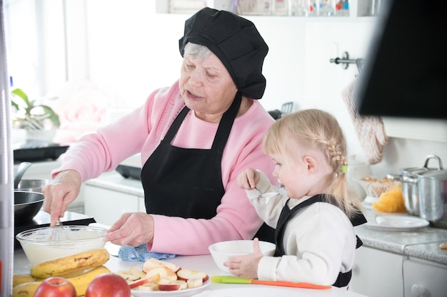 Familie in keuken een grootmoeder die deeg maakt voor pannenkoeken