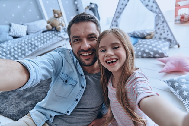 familie is het belangrijkste. zelfportret van jonge vader en zijn dochtertje glimlachend