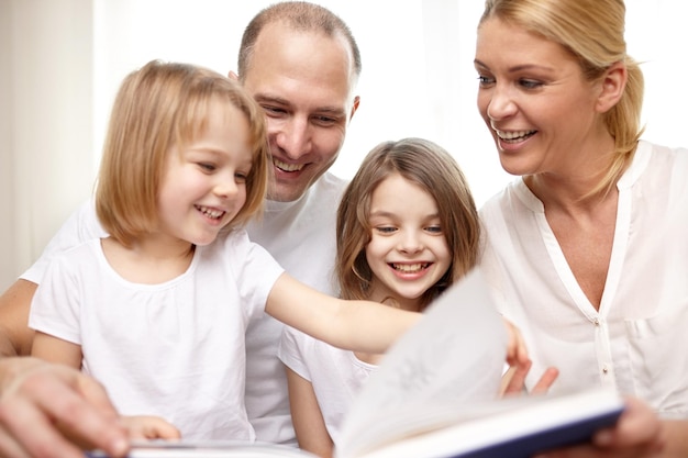 familie, jeugd, literatuur en mensen - gelukkige moeder, vader en kleine meisjes die thuis een boek lezen