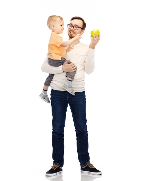 familie, jeugd, vaderschap, gezond eten en mensenconcept - gelukkige vader en zoontje met groene appel
