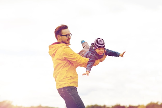 Foto familie, jeugd, vaderschap, vrije tijd en mensen concept - gelukkige vader en zoontje spelen en plezier buitenshuis