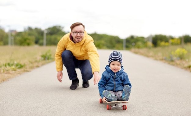 familie, jeugd, vaderschap, vrije tijd en mensenconcept - gelukkige vader en zoontje rijden op skateboard