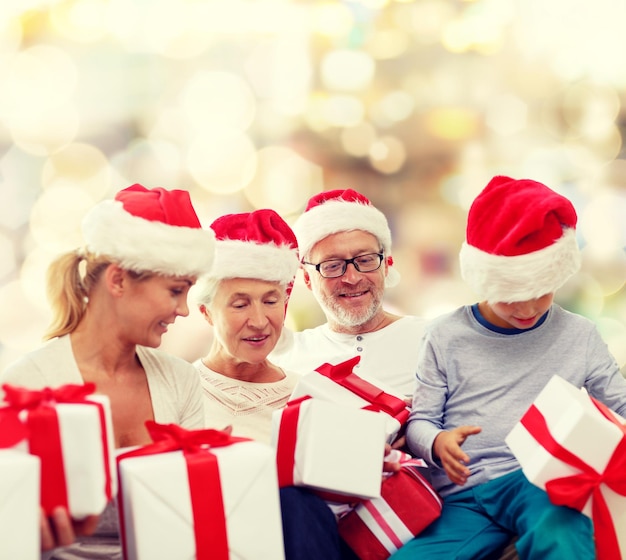 familie, kerst, generatie, vakantie en mensen concept - gelukkige familie in santa helper hoeden met geschenkdozen zitten over lichten achtergrond