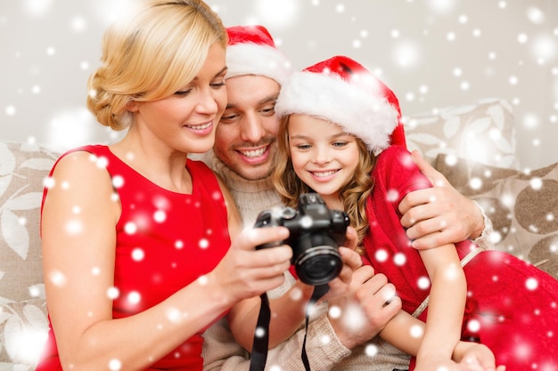 familie, kerst, kerst, winter, geluk en mensen concept - lachende familie in santa helper hoeden kijken naar foto's