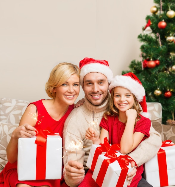 familie, kerst, kerst, winter, geluk en mensen concept - lachende familie in santa helper hoeden met veel geschenkdozen en Bengalen lichten