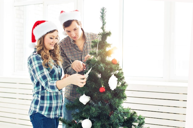 Familie, kerst, wintervakantie en mensen concept - gelukkig jong stel kerstboom thuis versieren.