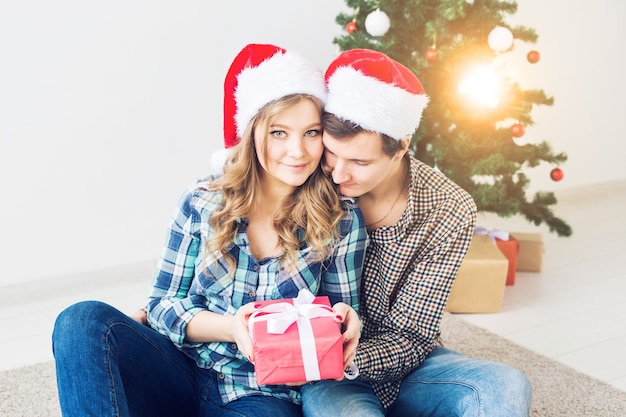 Familie, kerst, wintervakantie en mensen concept - gelukkig paar knuffelen in de buurt van kerstboom thuis.