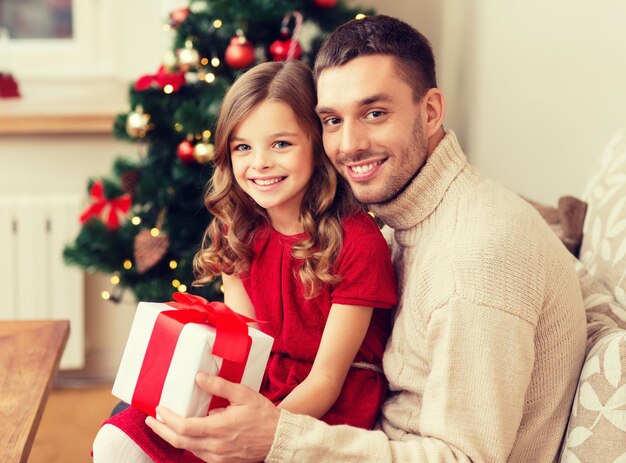familie, kerstmis, x-mas, geluk en mensenconcept - lachende vader en dochter met geschenkdoos