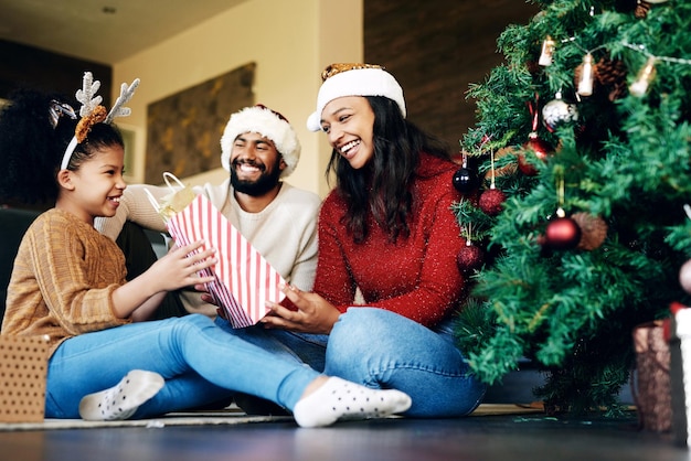 Familie kerstviering en cadeau geven blije glimlach en liefde op de vloer in huis feestelijke vakantie en verrassing Meisje moeder en vader vieren kerstmis met aanwezig geluk en tas in huis