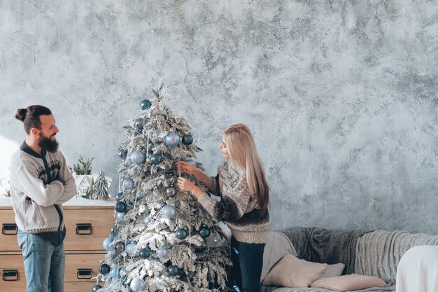 Familie kerstviering. Gelukkige paar genieten van het decoreren van fir tree thuis