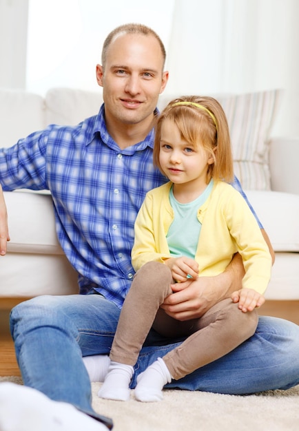 familie, kind en geluk concept - glimlachende vader en dochter zittend op de vloer thuis