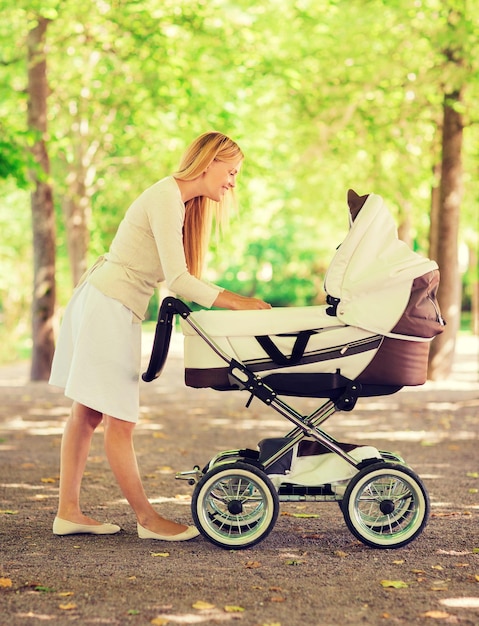 familie, kind en ouderschap concept - gelukkige moeder met kinderwagen in park