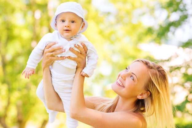 familie-, kind- en ouderschapsconcept - gelukkige moeder die kleine baby vasthoudt en opvoedt in het park