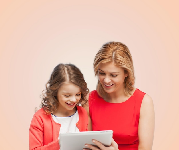 familie, kind en technologieconcept - glimlachende moeder en dochter met de computer van tabletpc