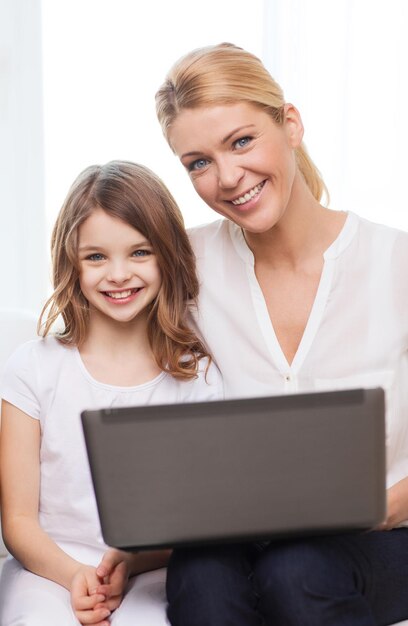 familie, kind, technologie en huisconcept - glimlachende moeder en klein meisje met laptop thuis
