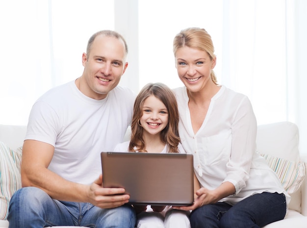 familie, kind, technologie en thuisconcept - lachende ouders en klein meisje met laptop thuis