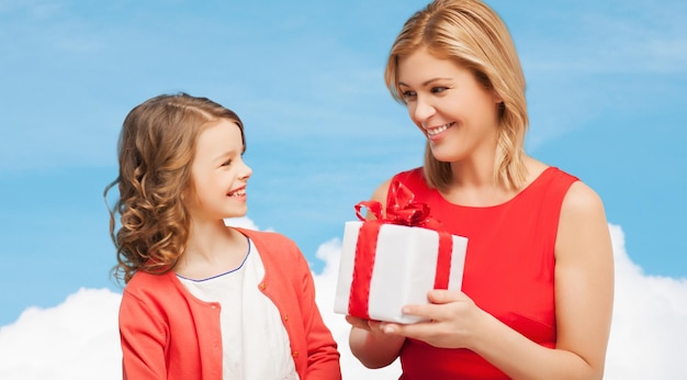 familie-, kind-, vakantie- en feestconcept - lachende moeder en dochter met geschenkdoos