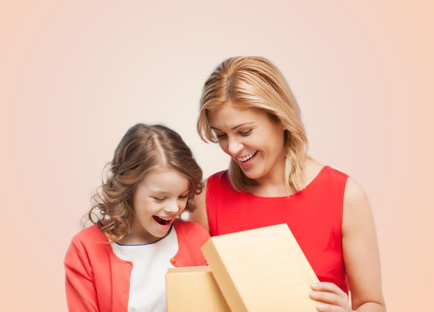 familie-, kind-, vakantie- en feestconcept - lachende moeder en dochter met het openen van een geschenkdoos